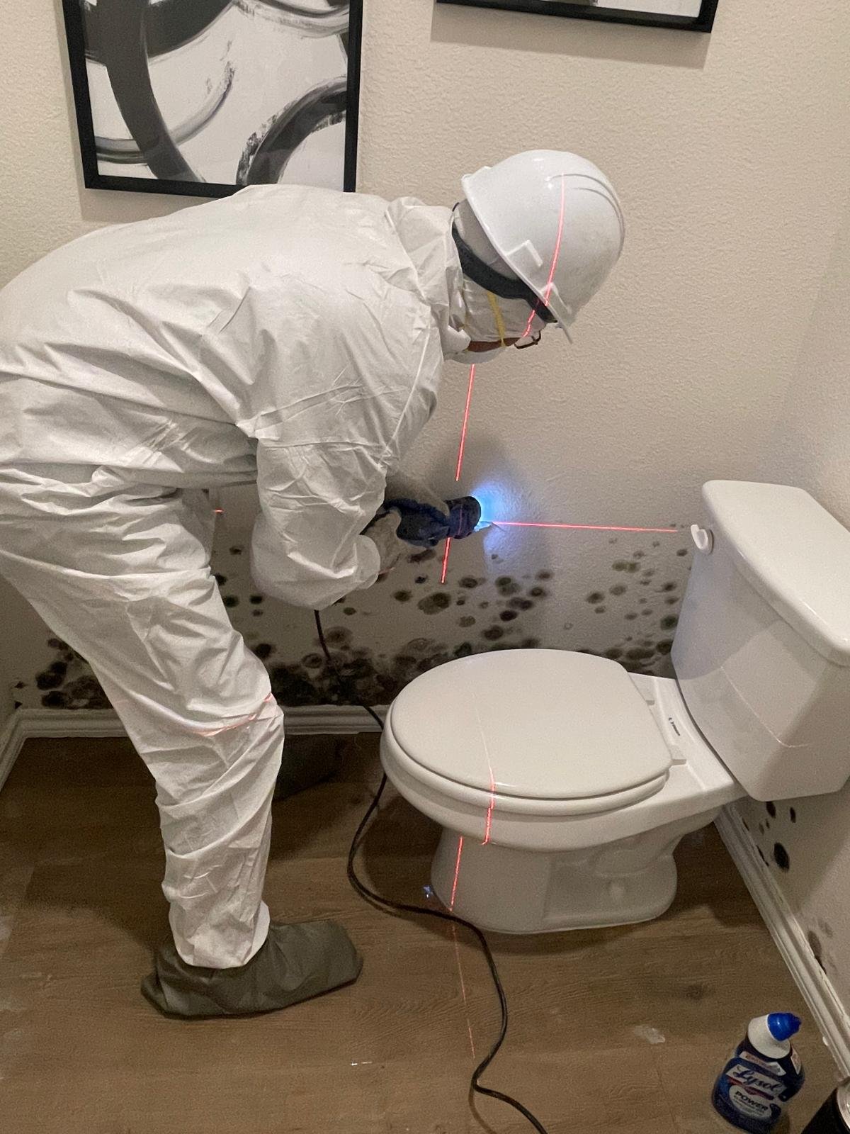 Personnel removing area of wall with molds